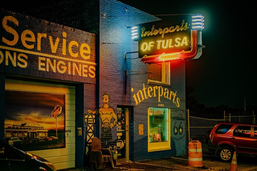 Store front of Interparts of Tulsa with neon sign and painted Golden Driller on front of building